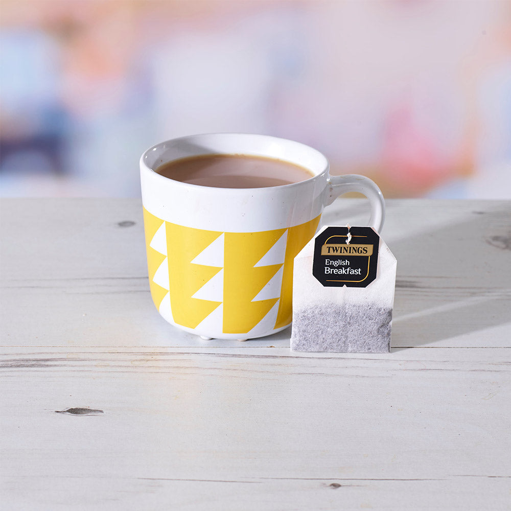 A cup of tea next to a Twinings English Breakfast String & Tag Tea Bag