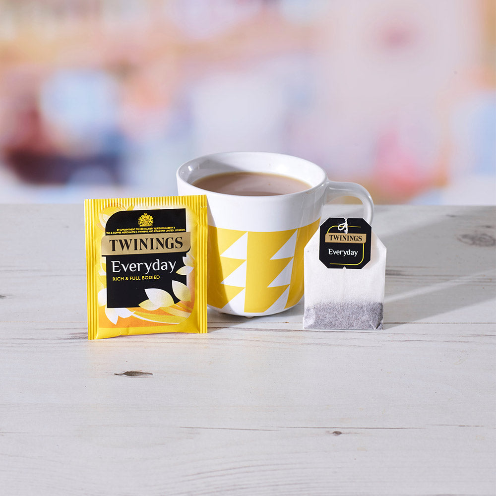 A cup of Tea next to a Twinings Everyday Envelope Tea Bag