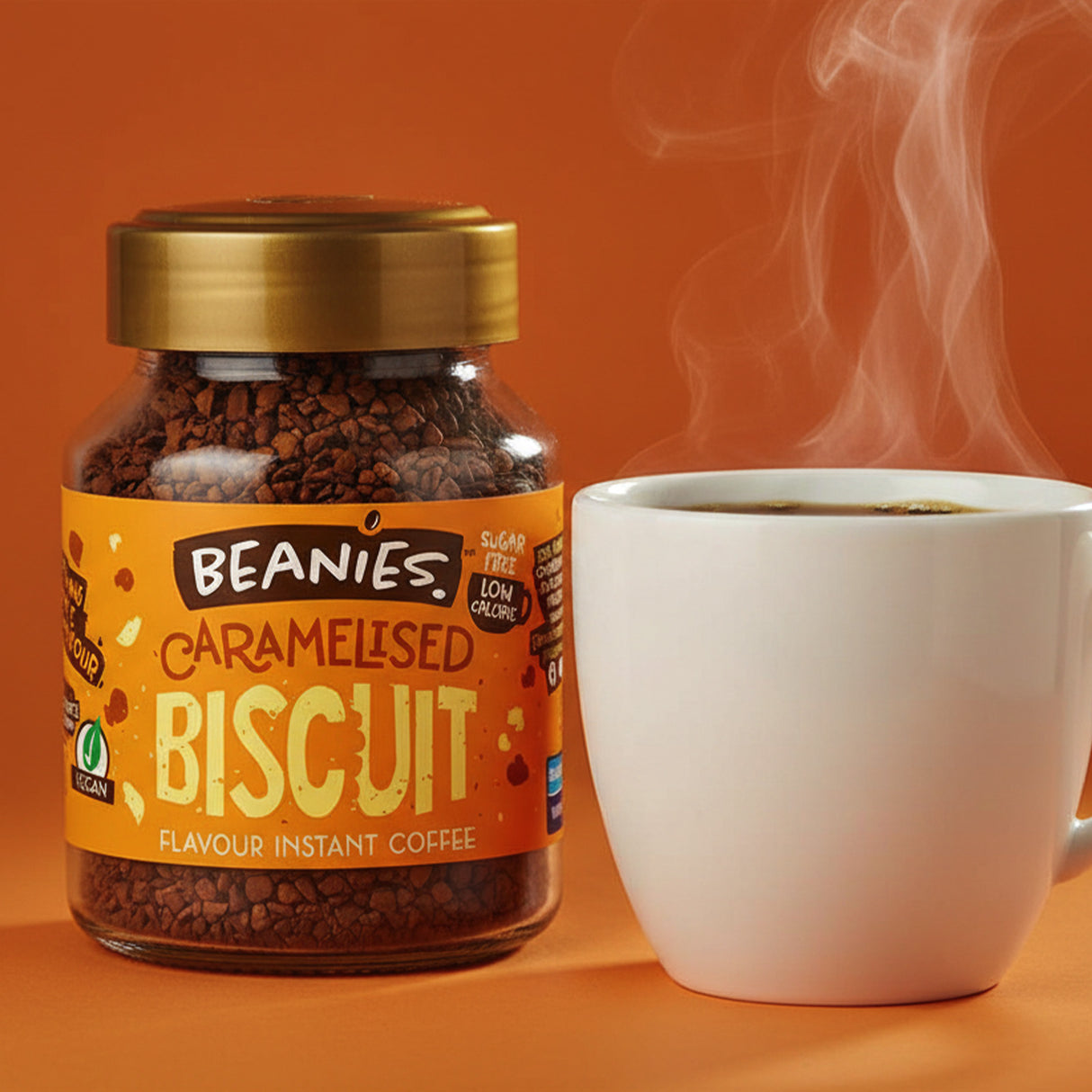 Jar of Beanies Caramelised Biscuit instant coffee with a steaming white cup on an orange background