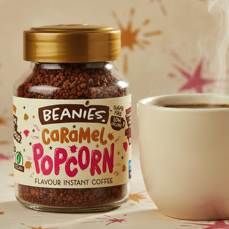 Jar of Beanies Caramel Popcorn instant coffee with a cup on a patterned surface