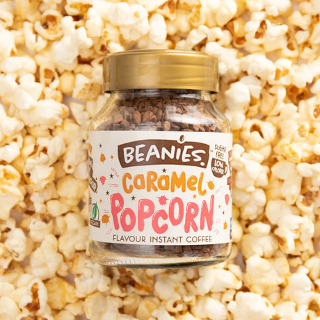 Jar of Beanies Caramel Popcorn flavored instant coffee surrounded by popcorn.