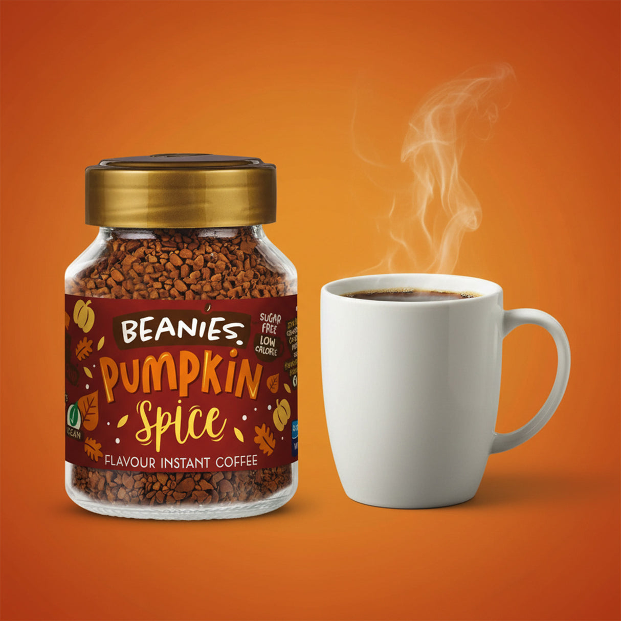 Jar of Beanies Pumpkin Spice instant coffee with a steaming white mug on an orange background