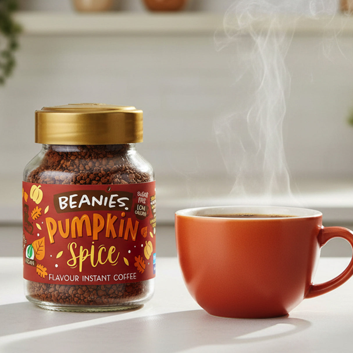 Jar of Beanies Pumpkin Spice instant coffee with a steaming cup on a light surface.
