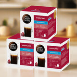 Three boxes of Dolce Gusto Americano Decaffeinated coffee capsules on a blurred background