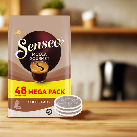 Senseo Mocca Gourmet coffee pads package on a wooden surface with a blurred kitchen background
