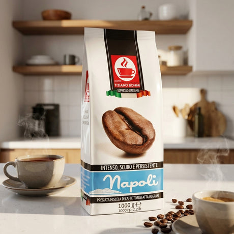 A 1000g bag of Tiziano Ronchi Napoli espresso coffee stands on a kitchen counter with coffee cups and scattered coffee beans in a warm, blurred kitchen setting.