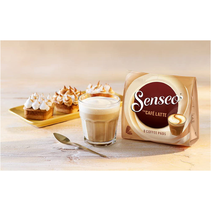 A packet of Senseo Cafe Latte, next to a cup of Caffe latte and some pastries