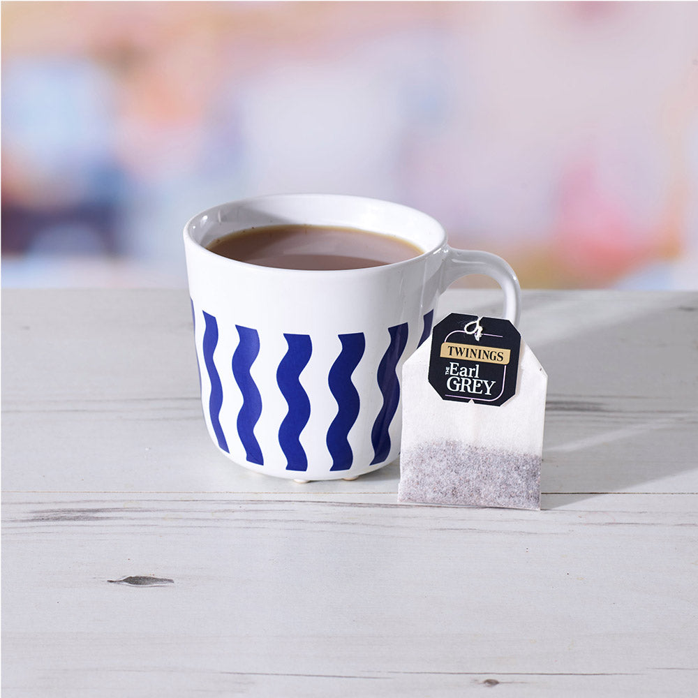A cup of tea next to a Twinings Earl Grey String & Tag Tea Bag