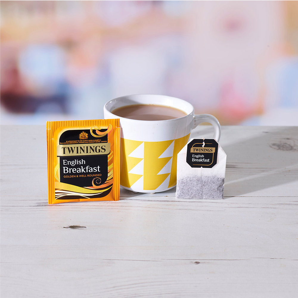 A cup of tea next to a Twinings English Breakfast Envelope Tea Bag